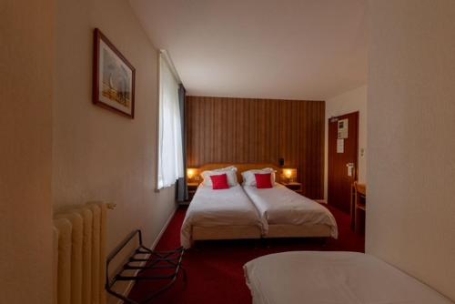 a hotel room with two beds with red pillows at Metropol Hotel in Calais