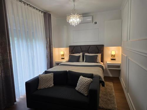 a bedroom with a bed and a couch and a chandelier at Guesthouse EL in Ogulin