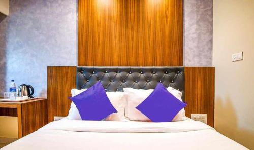 a bedroom with a bed with purple pillows at Hotel Suites Inn in Mumbai