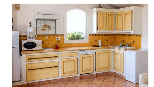 a kitchen with yellow cabinets and a sink and a microwave at Gîte Valensole in Valensole
