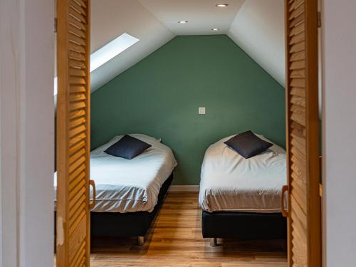two beds in a room with a green wall at La Petite Mazure in Tournai