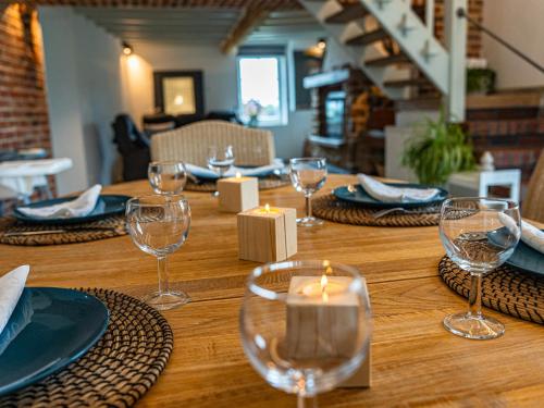a wooden table with glasses and a candle on it at La Petite Mazure in Tournai