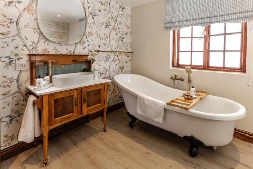 a bathroom with a tub and a sink and a mirror at Nassau Guest Farm in Stellenbosch