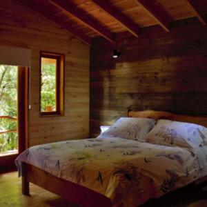 a bedroom with a large bed in a log cabin at Entre arrayanes lodge in Curarrehue
