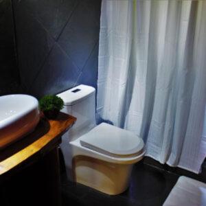 a bathroom with a white toilet and a sink at Entre arrayanes lodge in Curarrehue