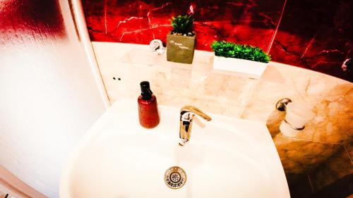 a white bathroom sink with a red wall at William's apartments - second cozy studio in Sveti Vlas