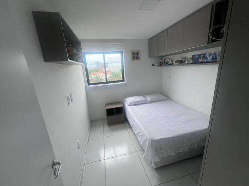 a small bedroom with a bed and a window at Quarto lovina e fest verão in Cabedelo