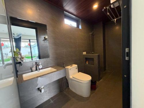 a bathroom with a toilet and a sink and a mirror at Phong Nha TuTu's House in Phong Nha