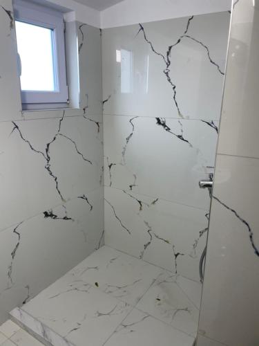a bathroom with white marble walls and a shower at Villa Rejan in Pogradec