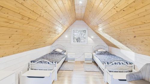 two beds in a room with wooden ceilings at Dębówka in Wilcze