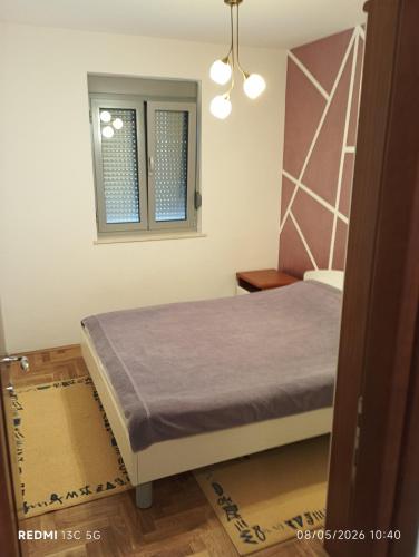a bedroom with a bed and a window at Apartment Grandis in Škaljari