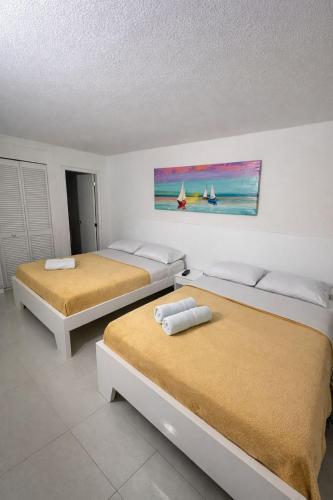 a room with two beds and a painting on the wall at Al Reef Apartamentos TOP in San Andrés
