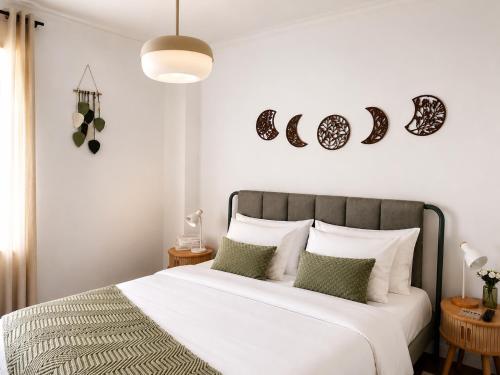 a bedroom with a bed with white sheets and green pillows at Pink House - Lisbon in Lisbon