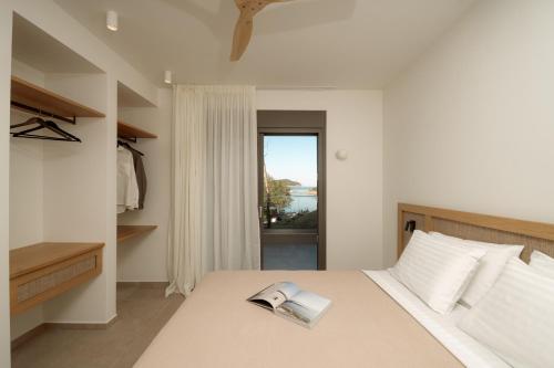 a bedroom with a bed with a book on it at Aktis Seaside Living in Iraklitsa