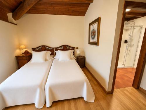 a bedroom with a large bed with white sheets at CASA DAS XACIAS, RIBEIRA SACRA in A Airoa