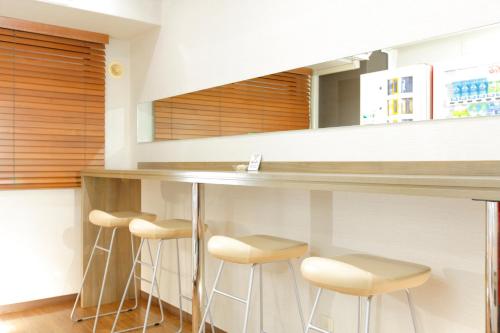 a kitchen with a bar with stools under a counter at HOTEL MYSTAYS Ueno Inaricho in Tokyo