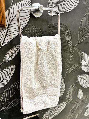 a white towel hanging on a wall with leaves at Agastya Vilas Resort in Dhandni