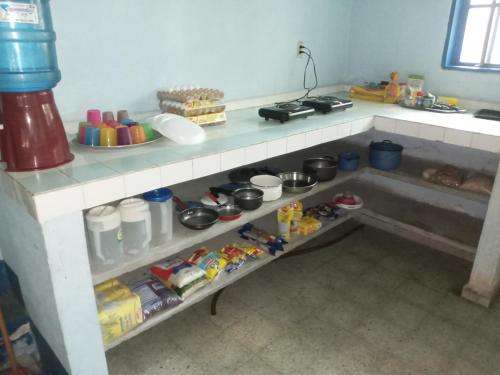 a kitchen with a shelf with food and drinks at Overlooking Budget Hotel in San Pedro Sula