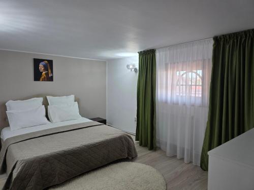 a bedroom with a bed and a window with green curtains at Vila Adina in Eforie Nord