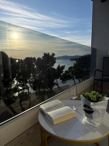 a table with a book and a wine glass and a window at Luxury apartment Alexandar in Makarska