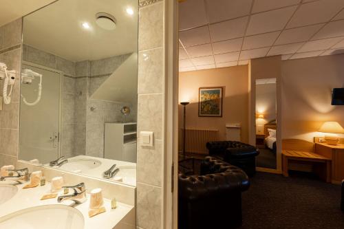 a bathroom with a tub and a sink and a bedroom at Metropol Hotel in Calais