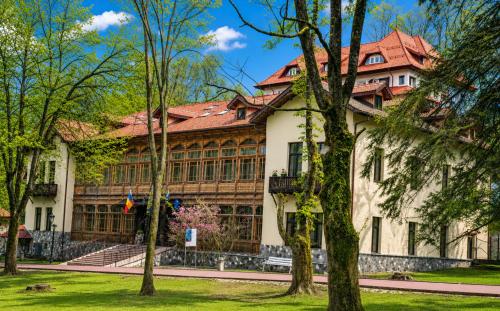 a building with trees in front of it at Hotel Regal 1880 - Boutique Hotel in Parcul Central Sinaia in Sinaia