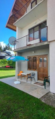 a house with a patio with a table and an umbrella at Kozorog Durmitor in Žabljak