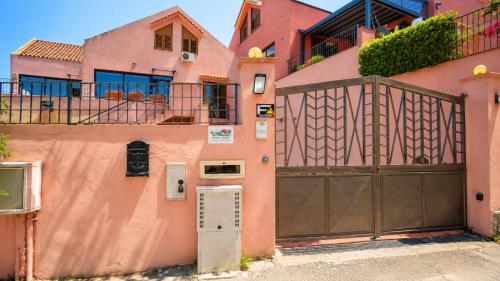 a pink house with a gate and a fence at Aloha Village - Bed&Pet in Messina