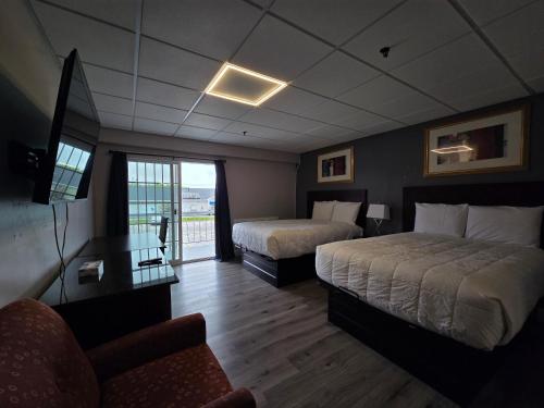 ein Hotelzimmer mit zwei Betten und einem Stuhl in der Unterkunft Saffron Inn in Auburn
