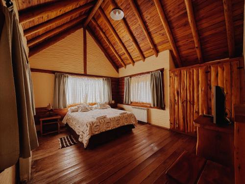 a bedroom with a bed in a room with wooden floors at Cabañas Aike in Caviahue