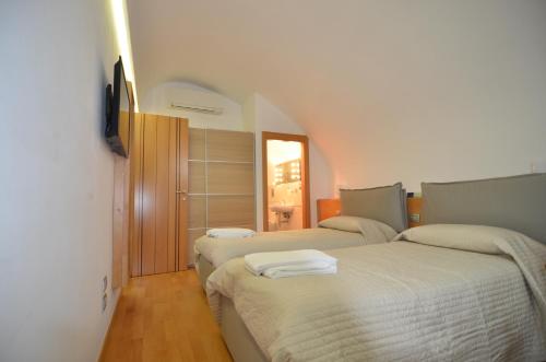ナポリにあるLa Strada Parlataのベッドルーム1室(ベッド2台、壁掛けテレビ付)