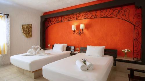 two beds in a hotel room with white towels at Hotel Xbalamqué Boutique & Spa in Cancún