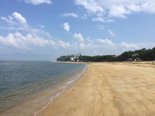 a sandy beach with the ocean on a cloudy day at South Wind Chalet in Itoshima