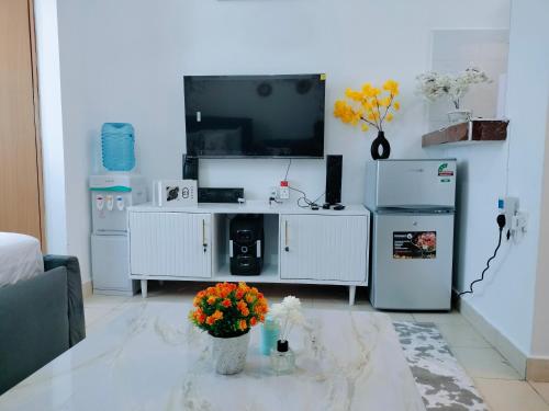 a living room with a tv and a table with flowers at Cutie coastal studios in Bamburi