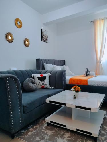 a living room with a blue couch and a bed at Cutie coastal studios in Bamburi
