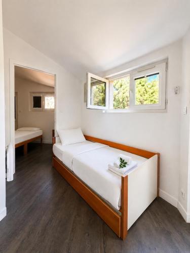a white bedroom with a bed and two windows at Charmant studio avec piscine 4 personnes in Fréjus