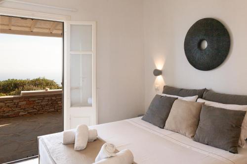 a bedroom with a large white bed and a large window at Astarte Sifnos in Artemonas