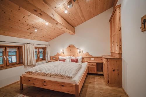 a bedroom with a bed and a wooden ceiling at Bergbauernhof Simmerl in Sachrang