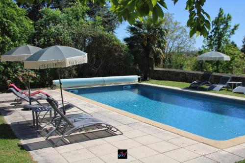 a swimming pool with two chairs and an umbrella at Domaine les Feuillants in Crouzilles