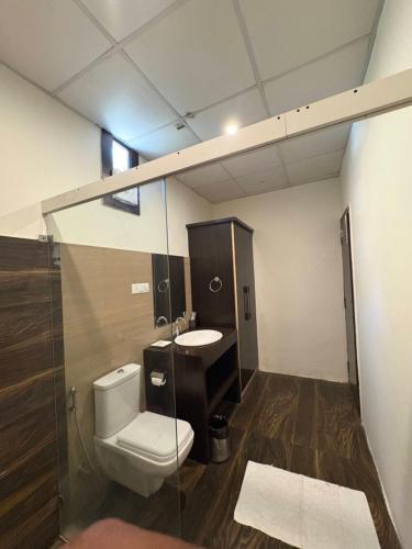 a bathroom with a toilet and a sink at Skywood by Vankuteer - Pool & Mountain view Rooms in Kandāghāt
