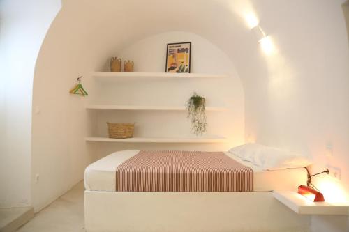 a bedroom with a bed with white walls and shelves at studio Barbouni in Aroniadika