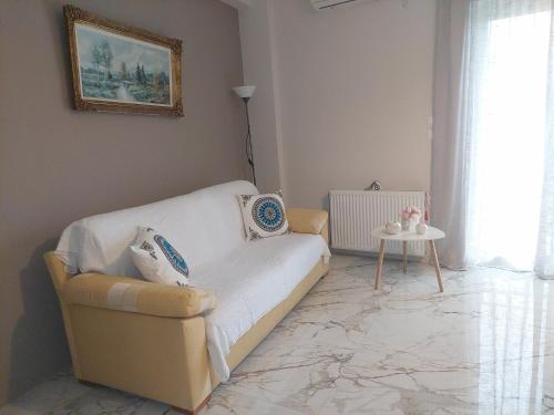 a living room with a white couch and a table at Claudia's Apartments in Aliveri