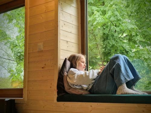 a girl sitting on a window seat looking out the window at Szalejówka Domki in Kłodzko