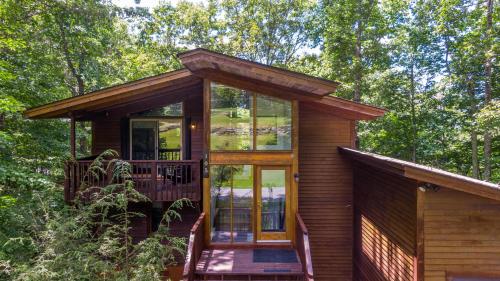 a small cabin with glass doors and a porch at Chasing Birdies in Beech Mountain
