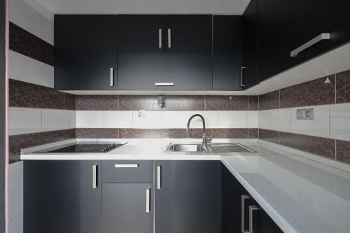 a kitchen with black cabinets and a sink at Apartmani Novia in Bibinje
