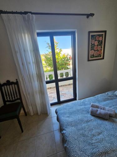 a bedroom with a bed and a chair and a window at Casa Sol in Carrapateira