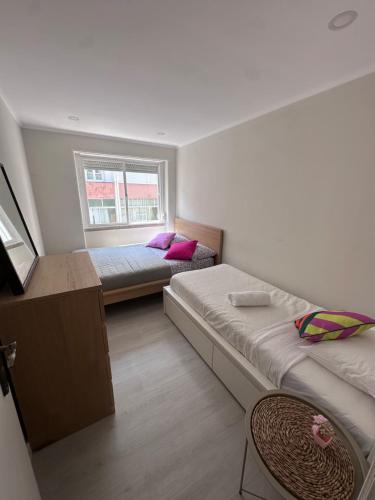 a small room with two beds and a window at Rooms Moscavide quartos in Lisbon