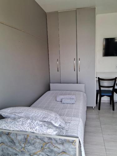 a bedroom with a bed and a chair and a tv at Studio em São José SC in São José