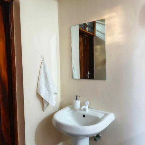 a bathroom with a white sink and a mirror at Meyer Stays in Kilifi