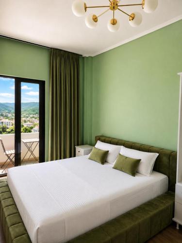 a bedroom with a large white bed with green walls at Sea Hotel in Ksamil